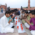 A large number of people sit and wait to break their fast during the holy month of Ramadan at the Badshahi Mosque