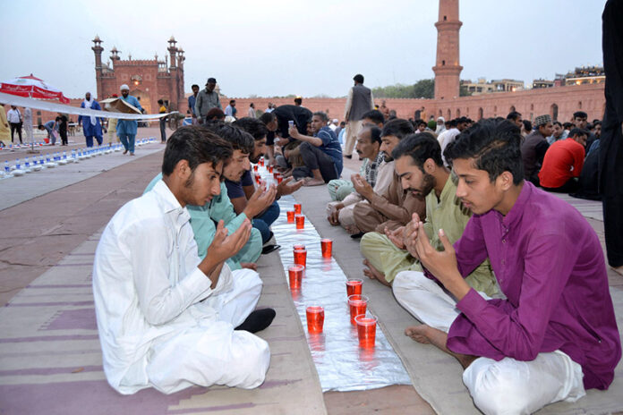 A large number of people sit and wait to break their fast during the holy month of Ramadan at the Badshahi Mosque