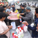 Volunteers are distributing sweetened milk and soda to thirsty passengers traveling on Shama Road during the fast-breaking period