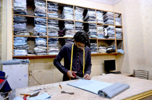 A tailor master at his work place is busy as per work demand due to preparation for upcoming Eid ul-Fitr.