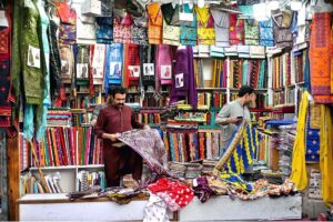 Shopkeeper displaying the unstitched clothes to attract the customers at Cloth Market in the Provincial Capital.