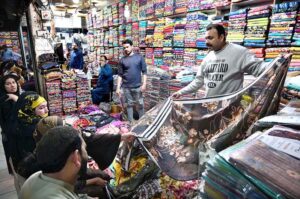 Shopkeeper displaying the unstitched clothes to attract the customers at Cloth Market in the Provincial Capital.