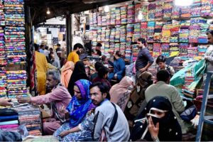 Shopkeeper displaying the unstitched clothes to attract the customers at Cloth Market in the Provincial Capital.