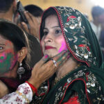 Hindu community women smear coloured powder on each other during the celebration of Holi, the Hindu spring festival of colours, at the Swaminarayan Temple