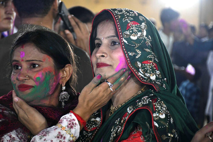 Hindu community women smear coloured powder on each other during the celebration of Holi, the Hindu spring festival of colours, at the Swaminarayan Temple