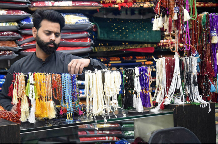 A shopkeeper is arranging rosaries (tasbih) made of beads and rare stones which are widely used by worshippers during the blessed month of Ramadan to attract customers in an Urdu Bazaar