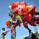 A vendor displays air filled balloons to attract children earning livelihood on Murree Road