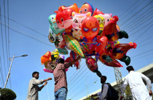 A vendor displays air filled balloons to attract children earning livelihood on Murree Road