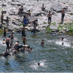 Youngsters swimming in a pond of water near Rawal Dam to cool themselves in hot weather in the Federal Capital
