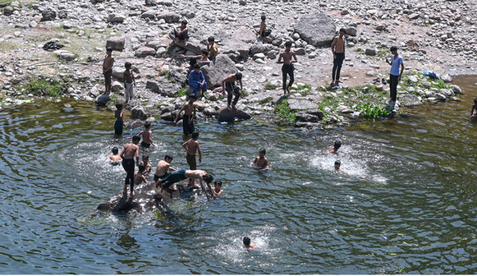 Youngsters swimming in a pond of water near Rawal Dam to cool themselves in hot weather in the Federal Capital