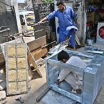 Workers install aspen pads in air coolers as temperatures soar in the capital