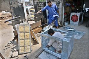 Workers install aspen pads in air coolers as temperatures soar in the capital