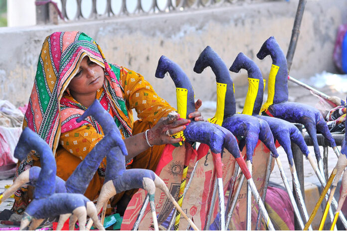 Gypsy woman preparing hand-made paper decoration stuff (Ghughu Ghoray) at roadside to earn livelihood