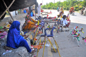 Gypsy woman preparing hand-made paper decoration stuff (Ghughu Ghoray) at roadside to earn livelihood