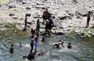 Youngsters swimming in a pond of water near Rawal Dam to cool themselves in hot weather in the Federal Capital