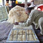 A worker busy preparing ‘khas’ (to be used in room-cooler) at his workplace in the Federal Capital