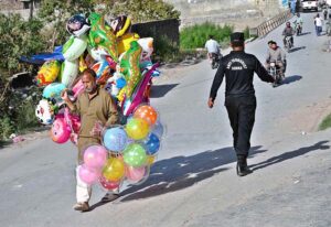 An elderly man strolls through a street in the capital, carrying balloons to earn a livelihood for his family