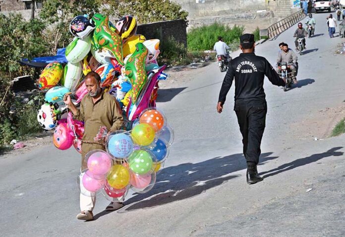 An elderly man strolls through a street in the capital, carrying balloons to earn a livelihood for his family