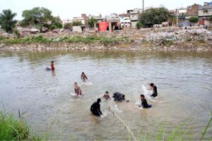 Children enjoy swim in Lower Jhelum Canal as the temperature rises day by day in the city