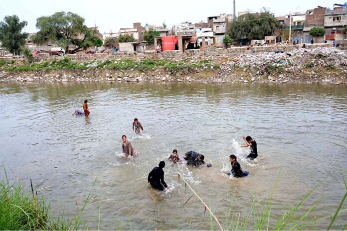 Children enjoy swim in Lower Jhelum Canal as the temperature rises day by day in the city