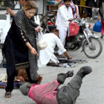 A woman gives mercy to a beggar crawling on the road at Bara Bazar