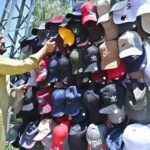 A vendor arranging and displaying caps to attract the customers along Lehtrar Road