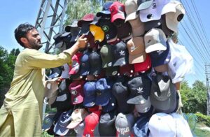 A vendor arranging and displaying caps to attract the customers along Lehtrar Road