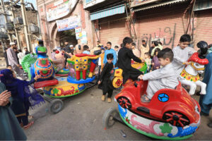 Children ride on a loader rickshaw to for outing on the second day of Eid al-Fitr celebrations in the city