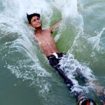 A youngster dives in the water canal during hot weather in the city