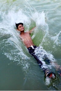 A youngster dives in the water canal during hot weather in the city
