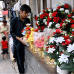 A vendor displays flower bouquet at his roadside setup to attract the customers