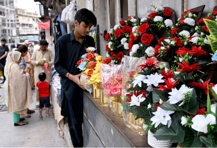 A vendor displays flower bouquet at his roadside setup to attract the customers