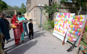 A woman experiences to shot balloons with a pallet gun during their visit to Lok Virsa on the second day of Eidul Fitr celebrations in the federal capital