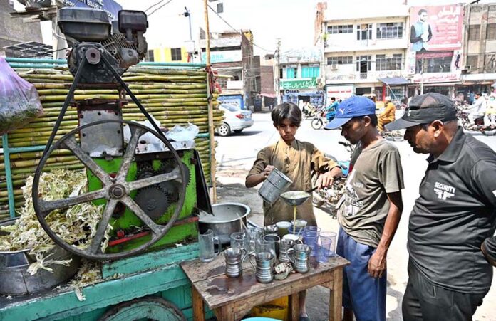 A vendor selling sugarcane juice at his roadside setup during hot weather in the city A vendor selling sugarcane juice at his roadside setup during hot weather in the city