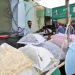 A vendor is selling umbrellas at his road side setup for livelihood