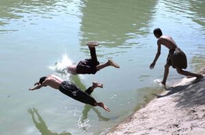 Youngsters jumping and bathing in the Chenal Mori Canal to get some relief from hot weather in the city