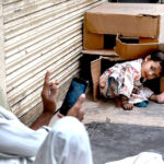 A minor girl playing on the footpath while her father capturing the moment in his cell phone