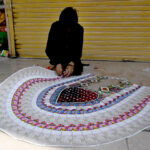 A vendor prepares currency note garland for sale at Aabpara market
