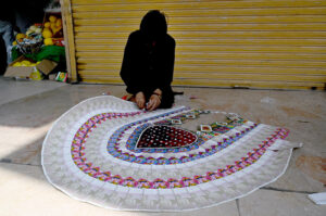 A vendor prepares currency note garland for sale at Aabpara market