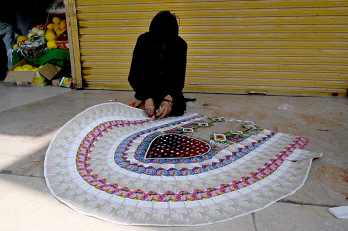 A vendor prepares currency note garland for sale at Aabpara market