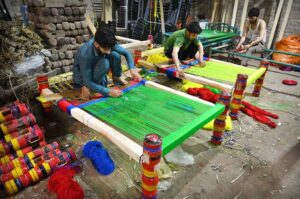 Workers are busy knitting traditional beds (Charpai) at their workplace in Namak Mandi area.