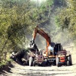 A view of an excavator and tractor cleaning local water canal to improve agricultural water supply