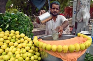 A vendor quenches the thirst of customers by selling freshly chilled lemonade, offering a cool respite amid the rising temperatures at his roadside setup.