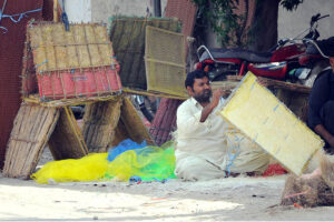 A worker is busy preparing Khas for the air cooler at his workplace.