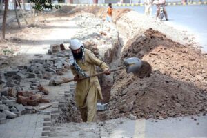 A daily wage labourer engaged in excavation work for laying a new pipeline near Iqbal Stadium
