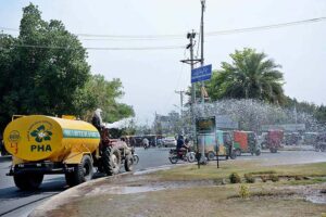 PHA workers showering water on plants to keep them fresh at GTS Chowk.