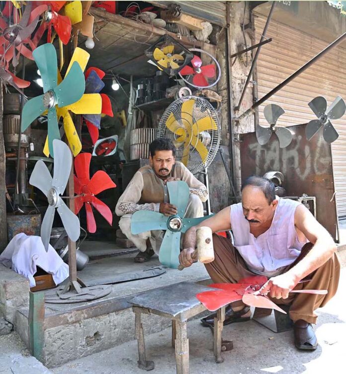 A mechanic is making room cooler fans at workplace in the city
