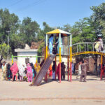 Families with their children enjoy the swings at Qasim Bagh Park