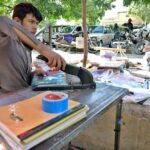 Worker busy in book binding at his workplace near Sitara Market in the Federal Capital