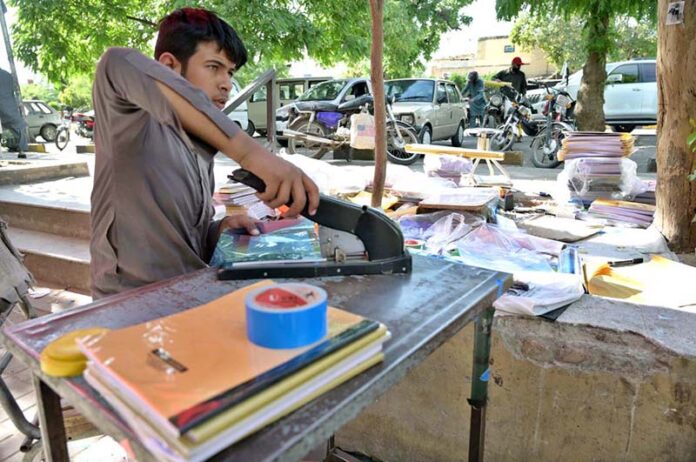 Worker busy in book binding at his workplace near Sitara Market in the Federal Capital